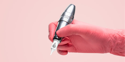 Pink-gloved artist holding a lightweight PMU machine.