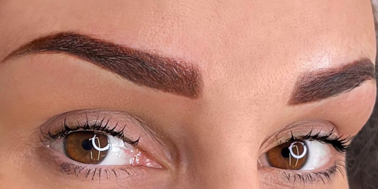 Close-up of a client’s eyes featuring a freshly completed set of symmetrical, brown ombre powder eyebrows.